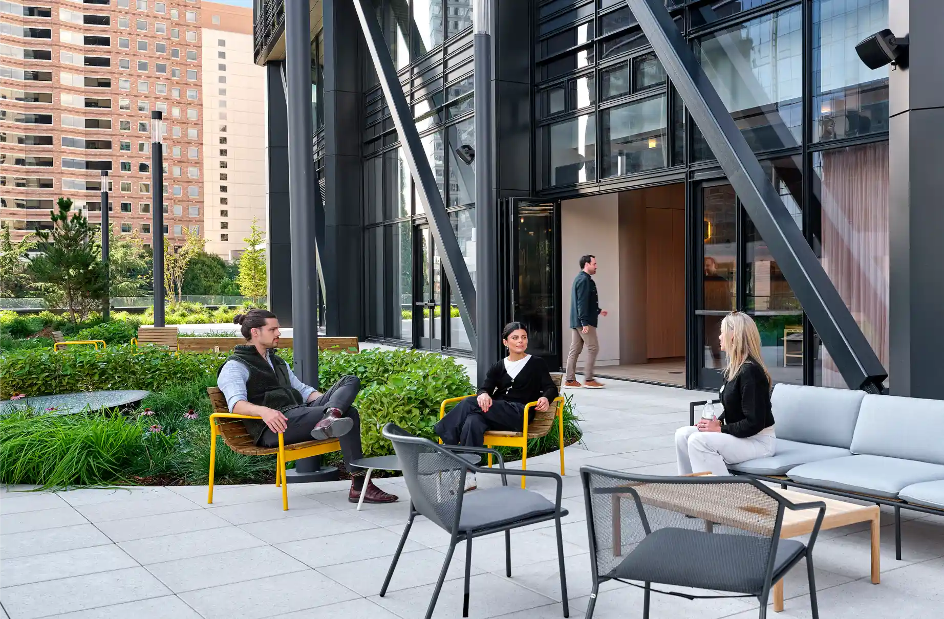 People sitting outdoors on chairs, engaging in conversation in a sustainable and community-focused environment. People sitting outdoors on chairs, engaging in conversation in a sustainable and community-focused environment.